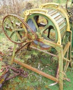Rusted heritage farm machine with large gear wheels awaiting restoration at Sligo Folk Park