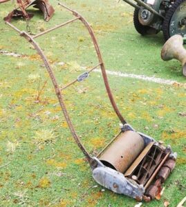 Rusty vintage push lawn mower in the grass before restoration at Sligo Folk Park
